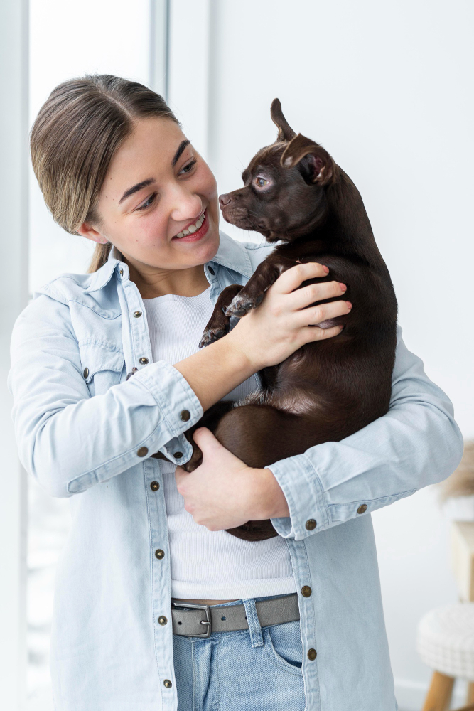 Smiling woman holding small brown dog